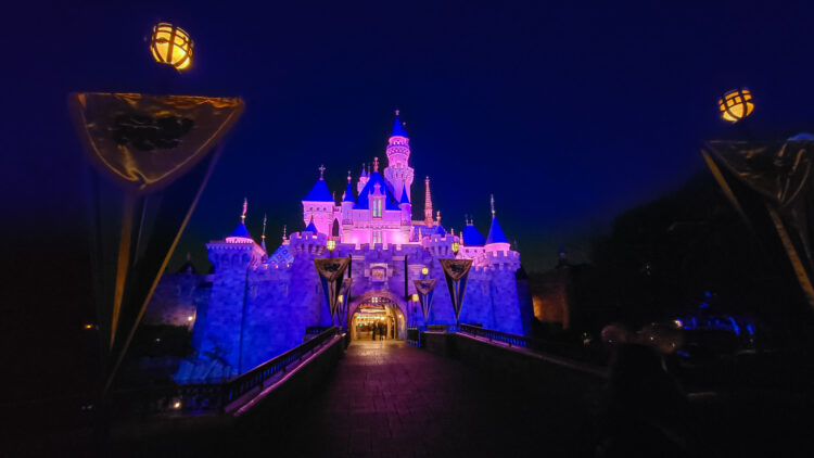 Sleeping Beauty Castle lit up at night at DIsneyland with nobody on the draw bridge