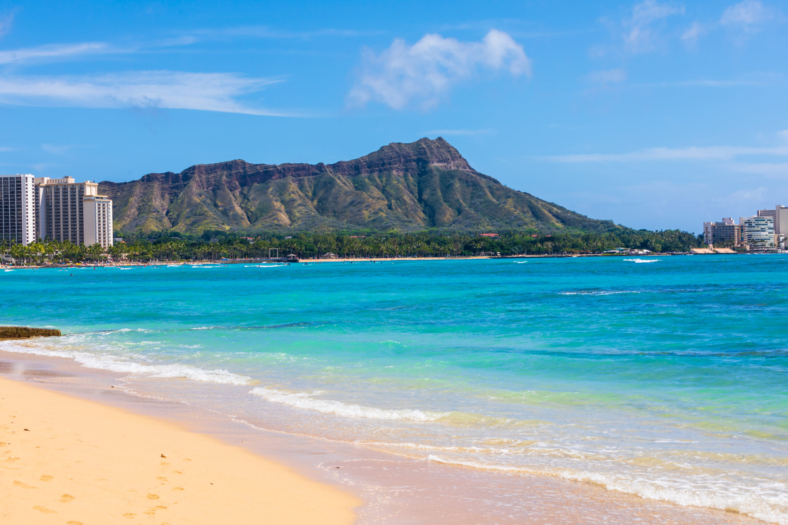 Photo of Diamond Head taken from Waikiki with ocean in and sandy beach in forefront.